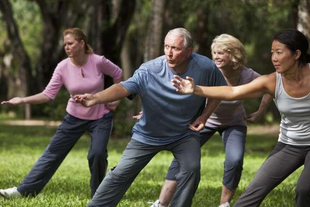 A group of adults practicing Tai Chi in a park.