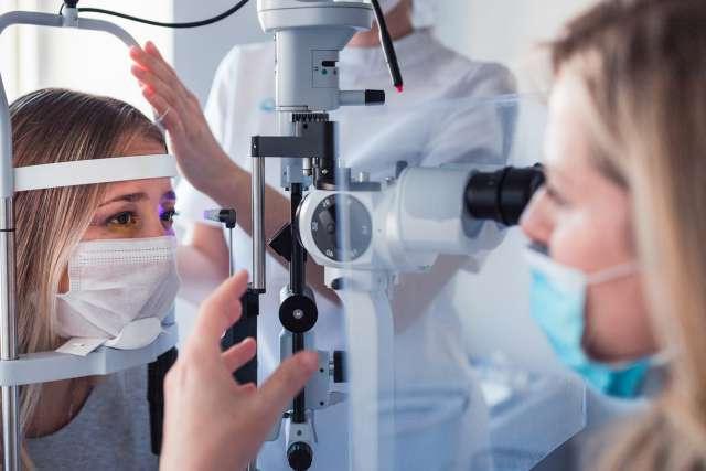 年轻女子在眼科医生处测量眼压时戴着医用防护口罩