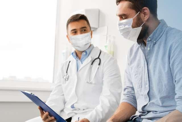 拿着写字板的医生和戴着口罩的病人在医院会面 