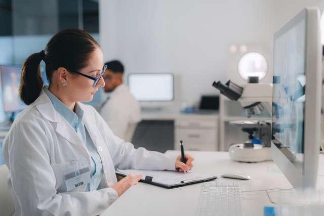 	女科学家在实验室里做研究和写作. 在计算机上分析结果, 显微镜和临床诊断记录, 药房和实验室技术员或医疗助理.